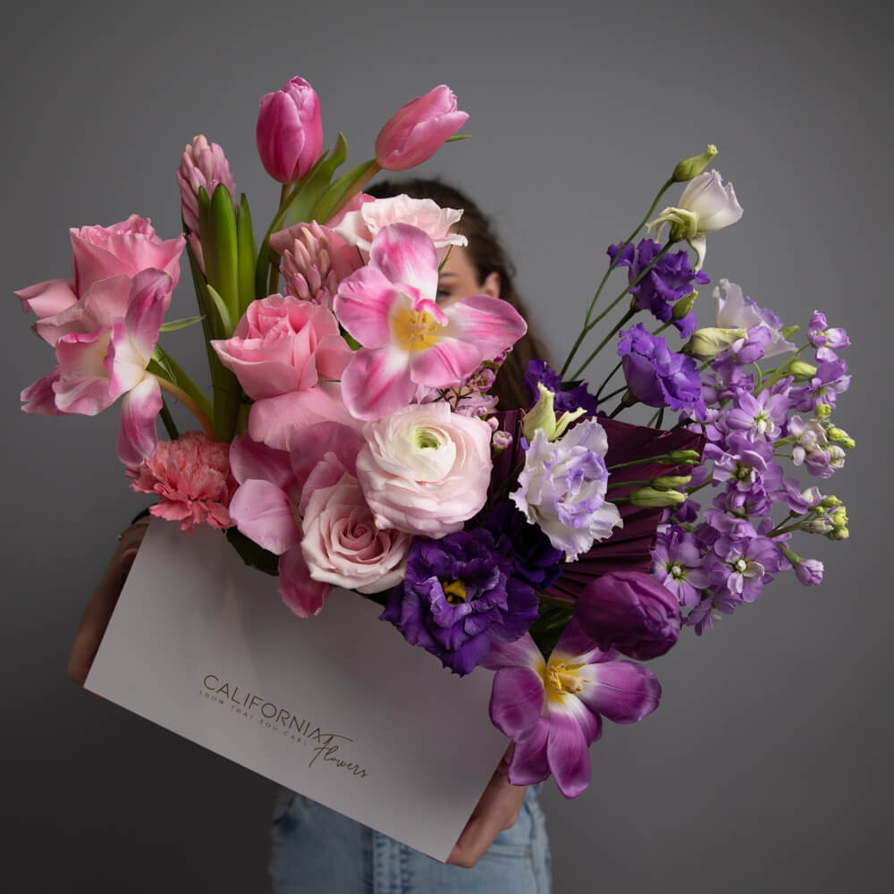 Arrangement in a box with purple and pink flowers