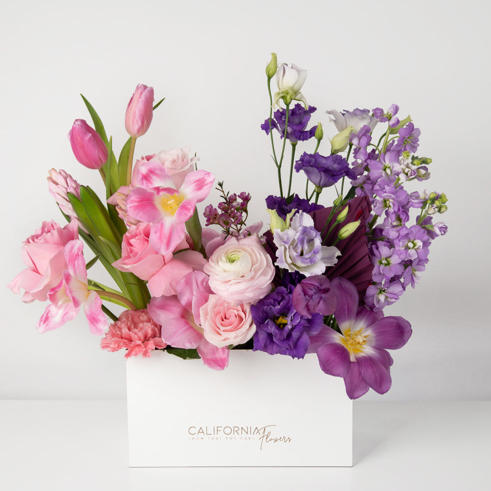 Arrangement in a box with purple and pink flowers